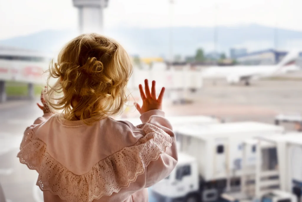 Bebé mirando por la ventana de un aeropuerto.