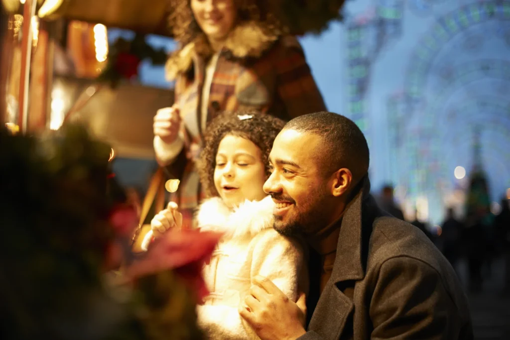 Familia joven en parque de atracciones por la noche divirtiéndose