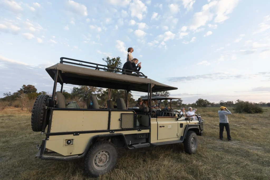 Grupo de personas alrededor de vehículos de safari al amanecer
